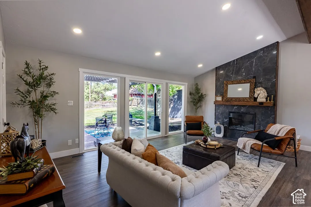 Spacious living area featuring wood-finish flooring, a contemporary fireplace with a dark stone-look surround, recessed lighting, and large sliding glass doors leading to the outdoor area