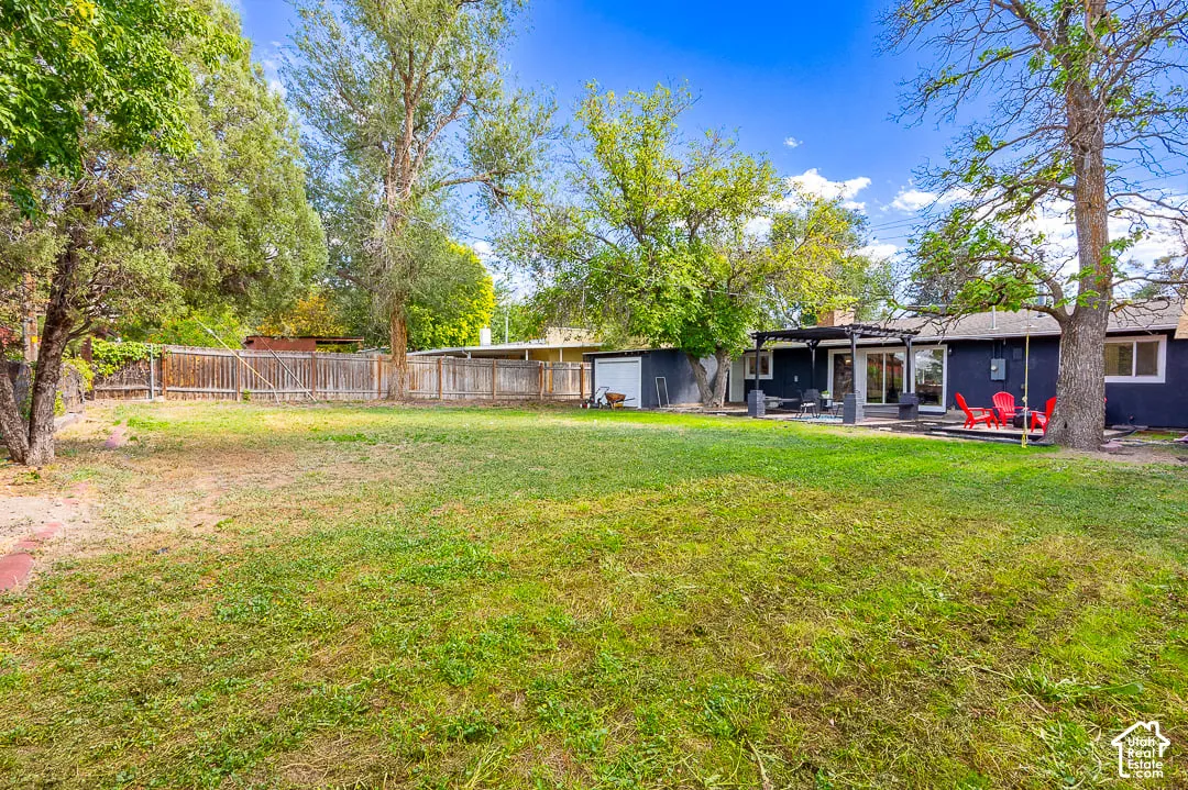 Expansive backyard featuring a manicured lawn, established trees, and a privacy fence
