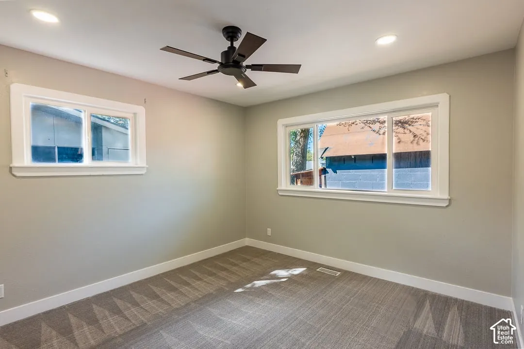 Recessed lighting, ceiling fan with integrated light, two distinct window styles, and textured carpet flooring