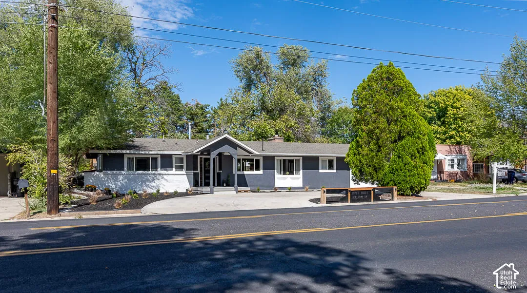 Single-story residence featuring a dark gray and white exterior, an arched entry, and multiple front-facing windows