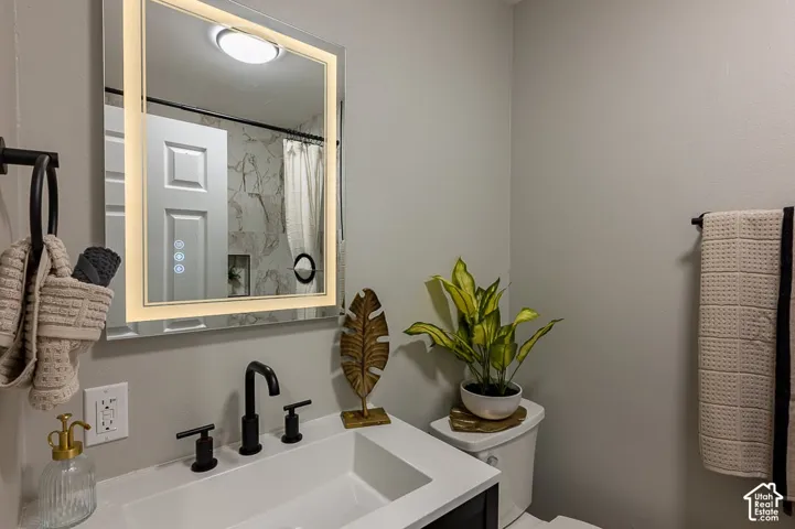 Vanity with white rectangular sink, matte black faucet, illuminated mirror, and integrated lighting