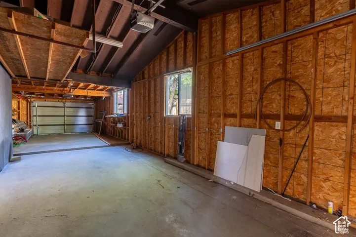 Spacious garage area featuring a concrete floor, exposed wood beam ceiling, and two windows
