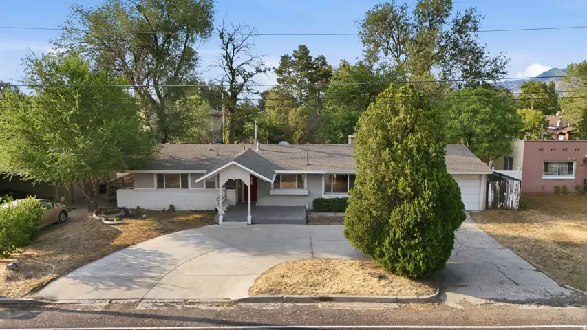 Circular concrete driveway, attached garage, covered entryway, and mature trees