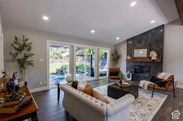Spacious living area featuring wood-finish flooring, a contemporary fireplace with a dark stone-look surround, recessed lighting, and large sliding glass doors leading to the outdoor area