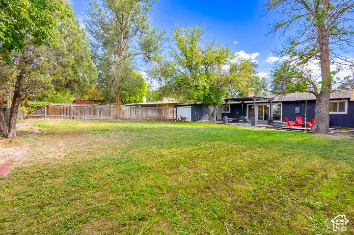 Expansive backyard featuring a manicured lawn, established trees, and a privacy fence