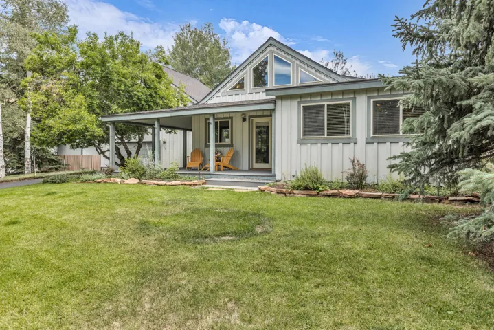 Exterior featuring a covered porch, board and batten siding, A-frame window, and a landscaped front yard