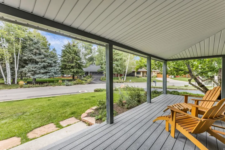 Covered porch with composite decking, white soffit, and grey support columns