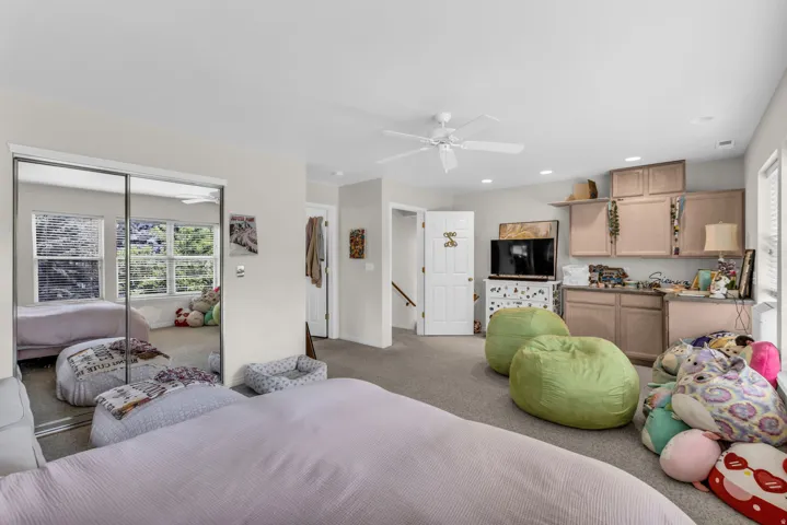 Carpeted flooring, mirrored sliding closet doors, ceiling fan, recessed lighting, and built-in cabinetry