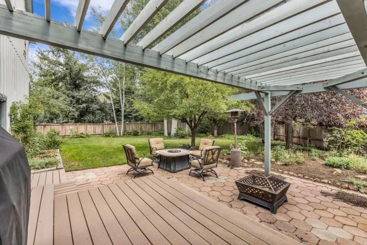Expansive outdoor living area featuring a slatted pergola, composite deck, and paver patio