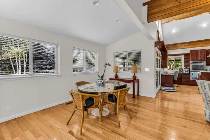 Recessed lighting, wood-finish flooring, multiple windows, vaulted ceilings with exposed wood beams, and a built-in kitchen desk