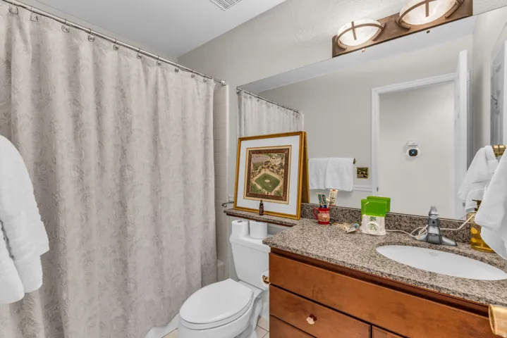 Vanity featuring a polished granite countertop, undermount sink, and wood-finish cabinetry