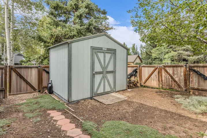 Storage shed with a pitched roof, surrounded by a wood privacy fence