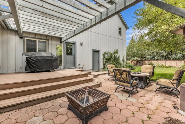 Outdoor living area featuring an expansive wood deck, a patio with hexagonal pavers, and a pergola structure
