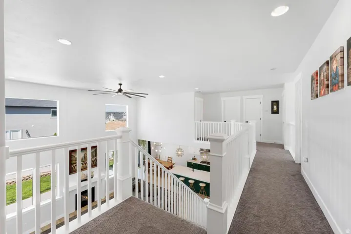 Upper-level hallway with carpet flooring, recessed lighting, white walls, and a ceiling fan