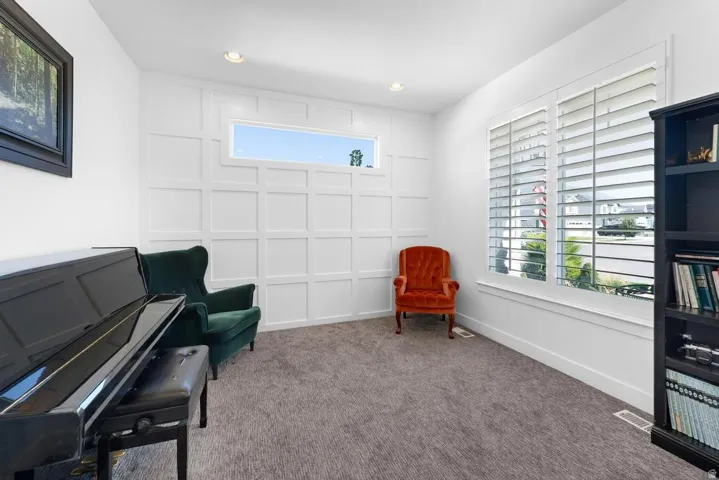 White wall paneling, recessed lighting, carpeted flooring, and plantation shutters
