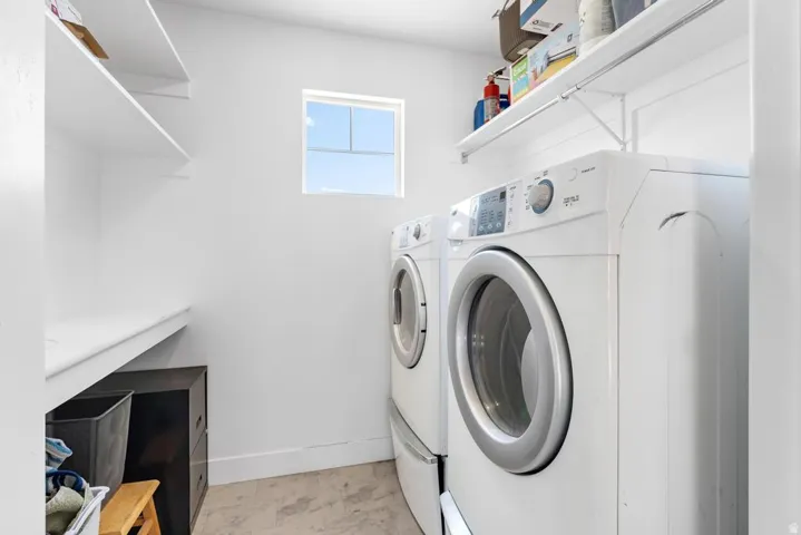 White walls with recessed window, laundry appliances, built-in shelving, and light-toned flooring