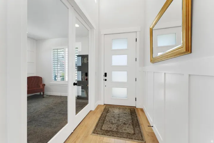 Entryway featuring wood-finish flooring, white board and batten wainscoting, and a modern front door with frosted glass panels