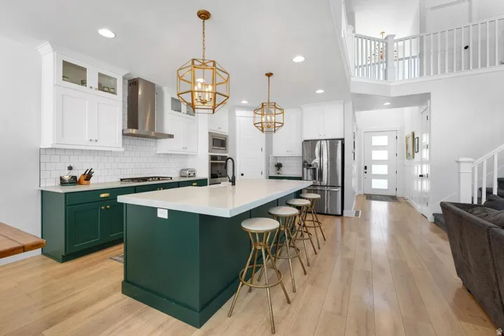 Open-concept kitchen with a large island featuring a light-toned countertop, white subway tile backsplash, and light wood-finish flooring
