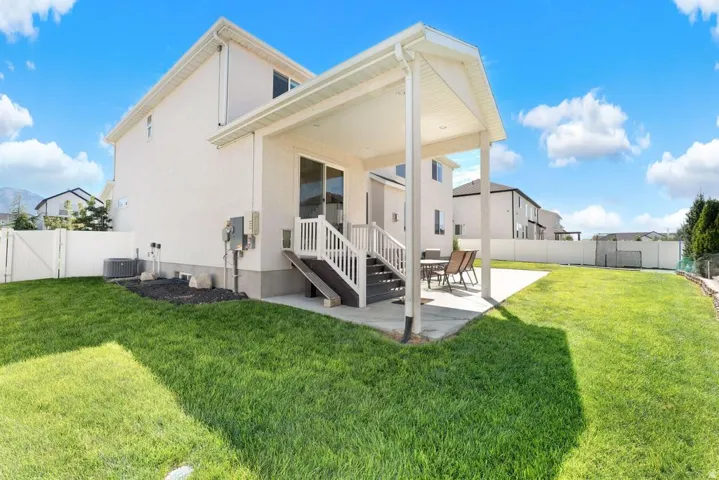 Expansive lawn, covered patio, white privacy fencing, concrete patio, and exterior siding