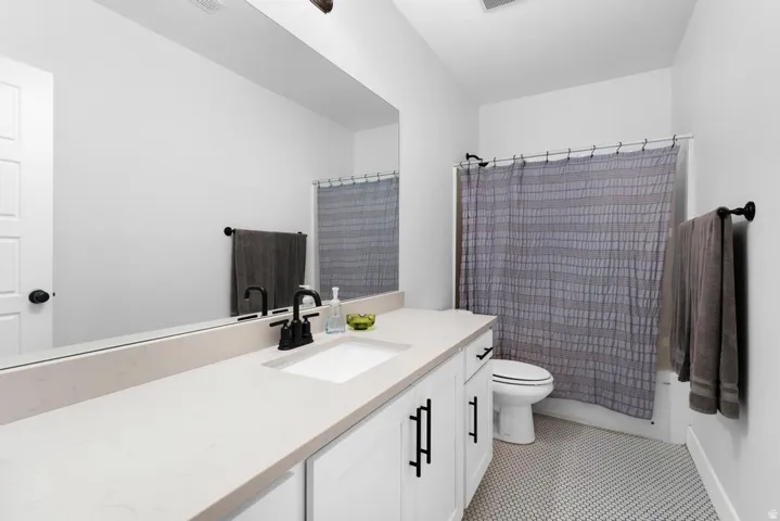White shaker-style cabinetry with matte black hardware, integrated single-basin sink, light-toned countertop, and full-width mirror