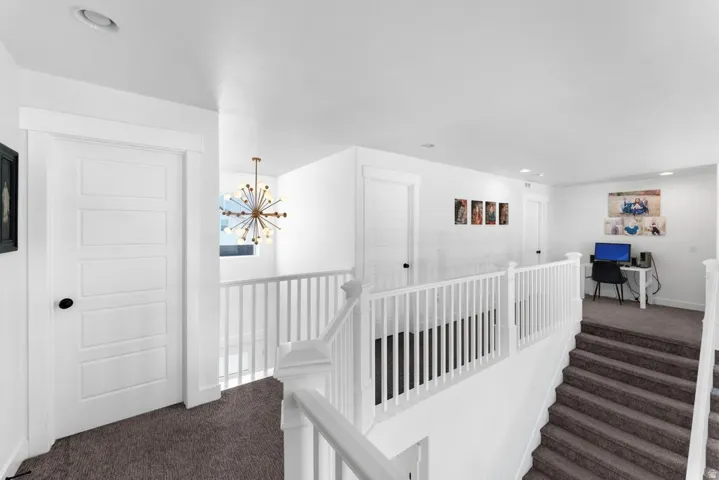 Upper-level landing with neutral carpeting, white balusters, and recessed lighting