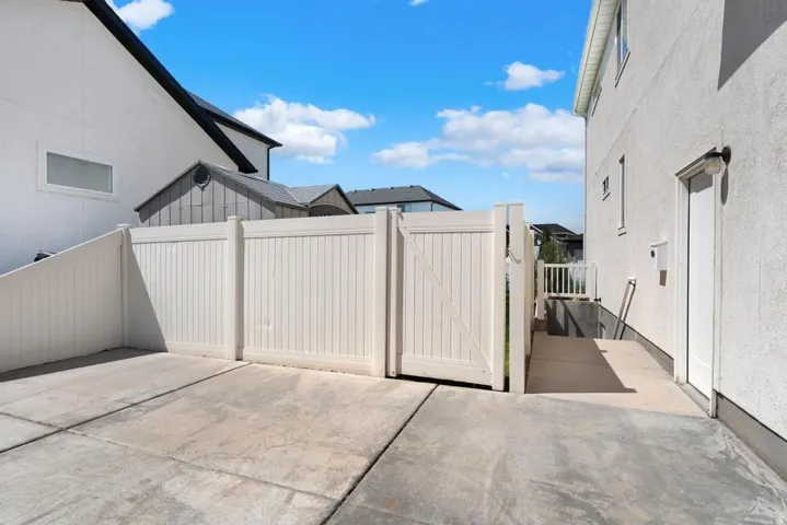 Concrete patio featuring a white vinyl fence and gate