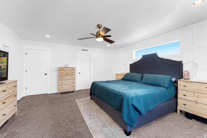 Recessed lighting, ceiling fan with light fixture, high windows, white paneled accent wall, and paneled interior doors