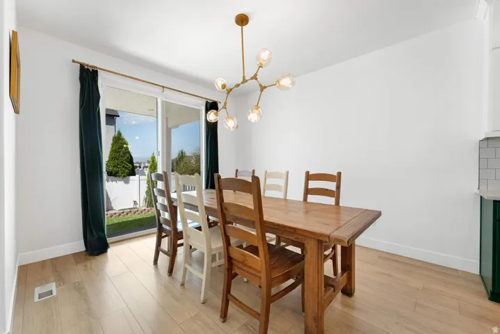 Wood-finish flooring throughout, modern branch-style chandelier, and white walls