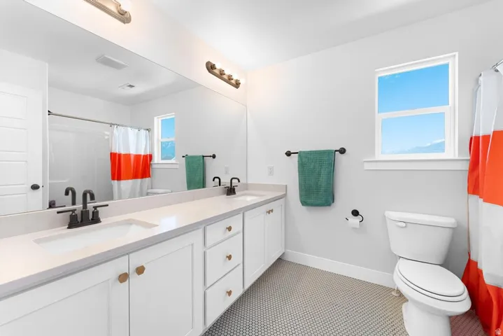 Dual vanity with white cabinetry, light-toned countertops, and matte black fixtures