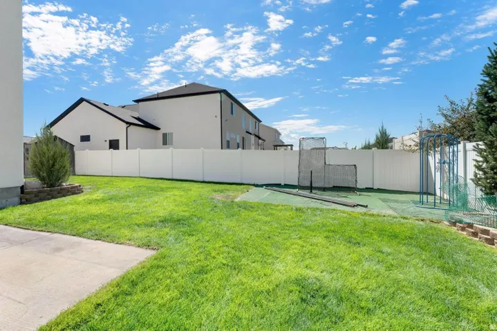 Manicured lawn, white privacy fence, concrete patio, and a raised planter bed