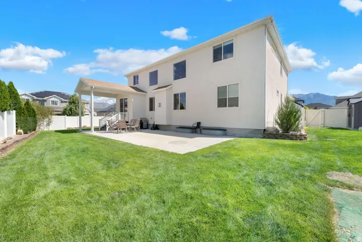 Expansive fenced backyard featuring a covered patio, concrete patio, and substantial lawn area