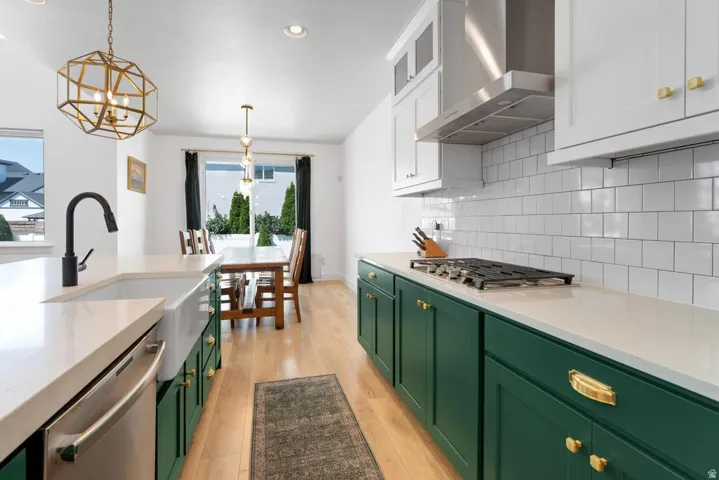 Contemporary kitchen featuring contrasting green and white cabinetry, a farmhouse sink, stainless steel appliances, and wood-finish flooring