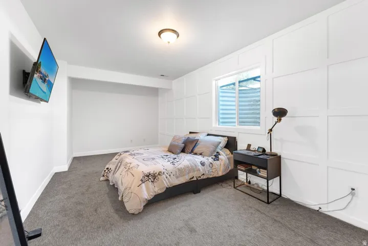 White paneled accent wall, neutral carpeting, recessed window, and flush mount ceiling light fixture
