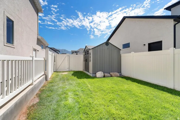 Fenced backyard featuring a manicured lawn, a detached storage shed, and a privacy fence