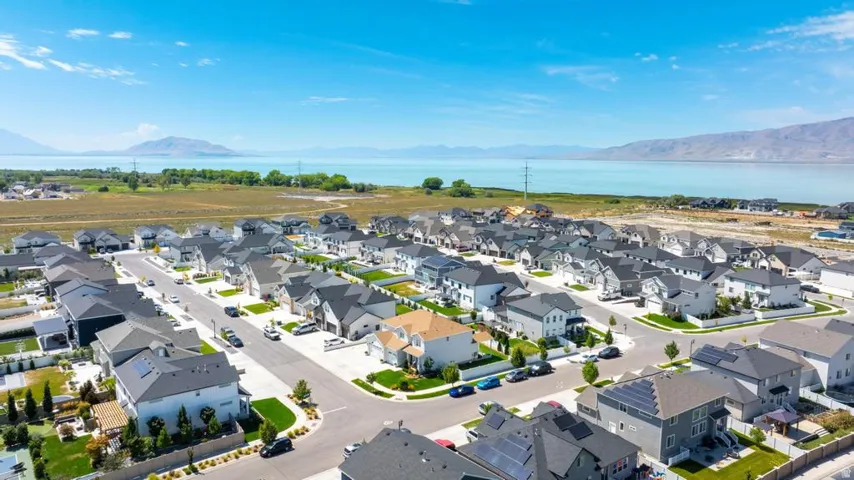 Expansive residential development with a modern architectural aesthetic, featuring a water body and mountainous backdrop