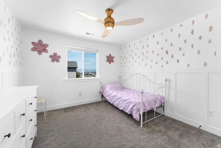 Recessed window, ceiling fan with integrated lighting, wall paneling, and carpet flooring