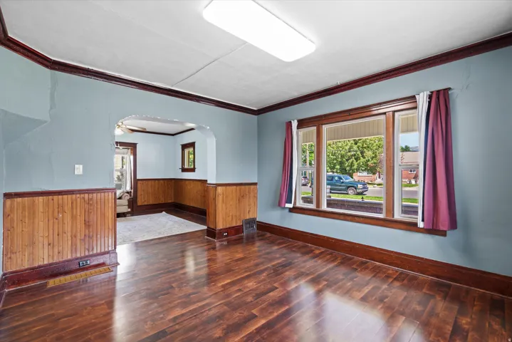 Wood-finish flooring, paneled wainscoting, and a large window with wood trim