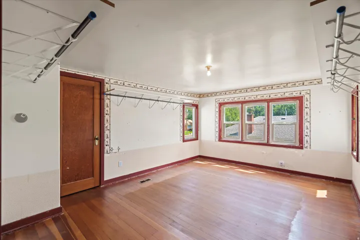Wood-finish flooring, multiple windows, a wood-panel door, and a ceiling-mounted light fixture