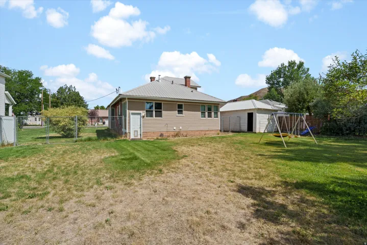 Chain-link fenced yard with a detached shed and a swing set