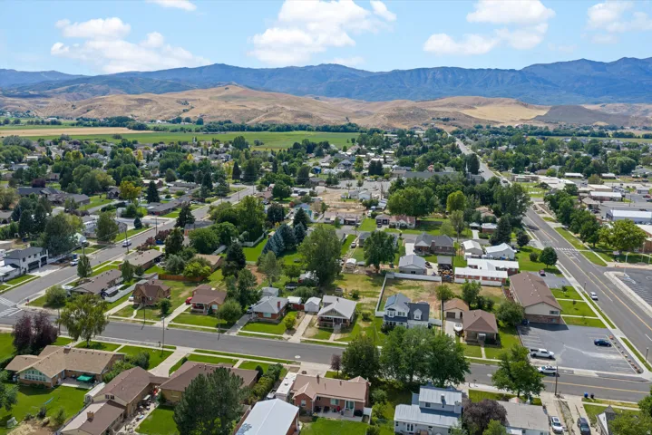 Aerial view of established residential neighborhood featuring tree-lined streets, diverse single-family homes with varied architectural styles, and expansive mountain backdrop