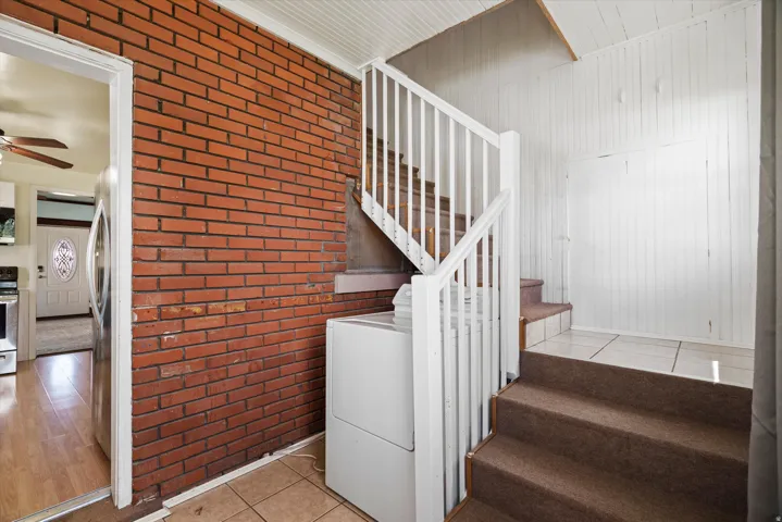 Exposed brick accent wall and open staircase with white railings and wood-finish treads