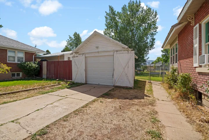 Detached garage with a roll-up door, paved driveway, and additional side access