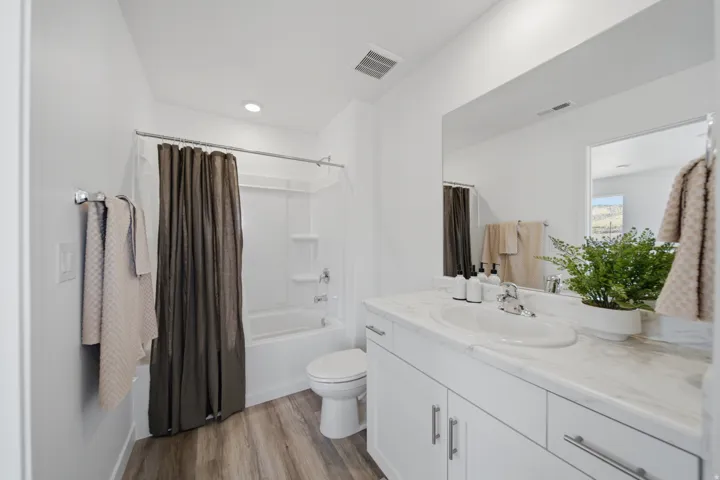 Vanity with dual-handle faucet, white cabinetry, integrated sink, and white countertop