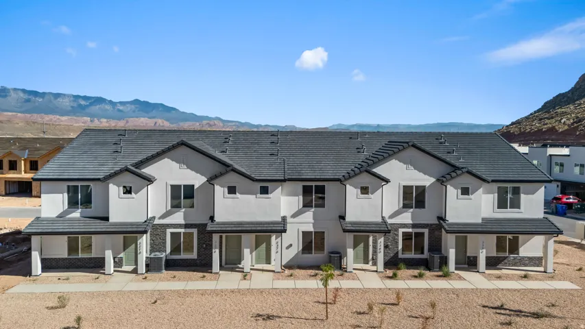 **All photos are of a similar staged model**Modern townhome exterior with white stucco siding, dark gray roof, stone veneer accents, and covered entryways