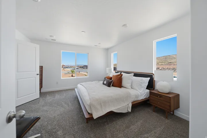 White paneled door, gray carpet, multiple recessed lights, and large windows with mountain and neighborhood scenery