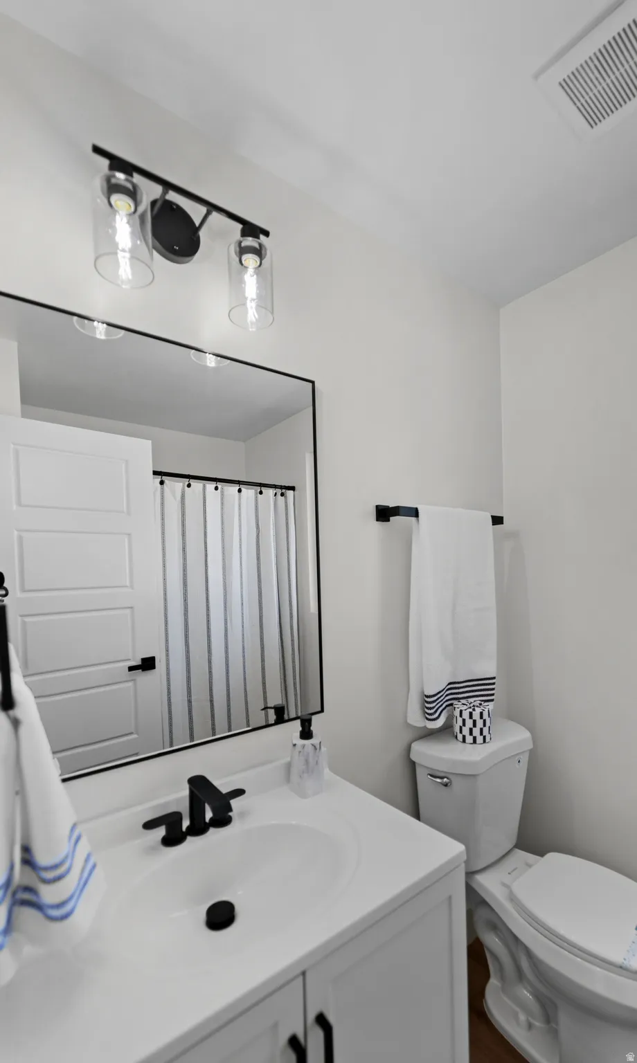 White vanity with integrated sink, matte black faucet, and framed mirror