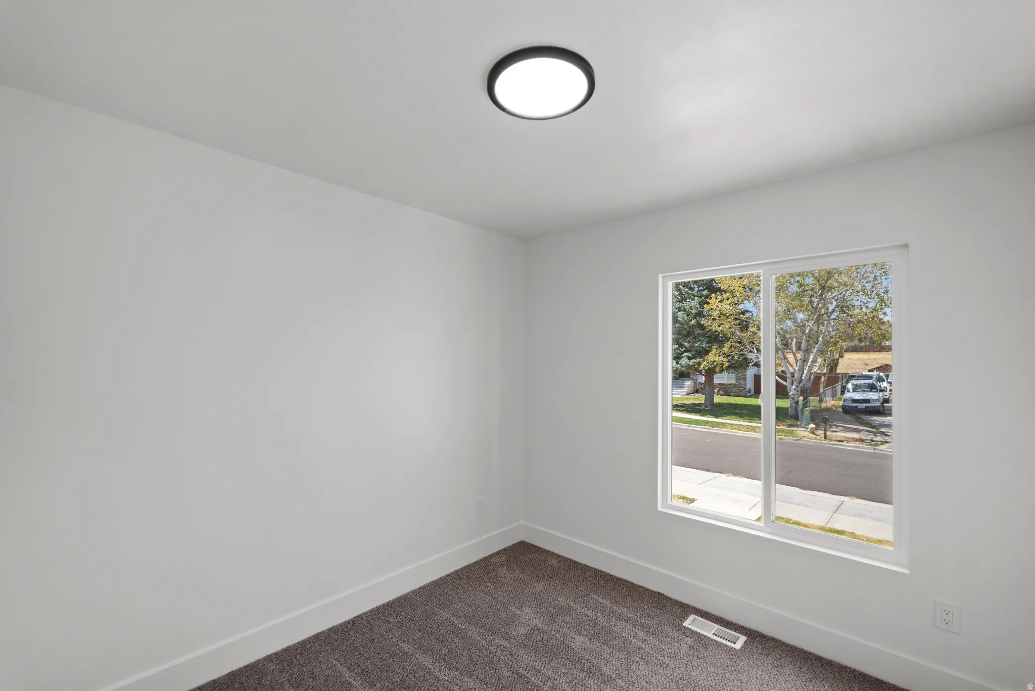 Neutral wall finishes, a large window, and a flush-mount ceiling fixture