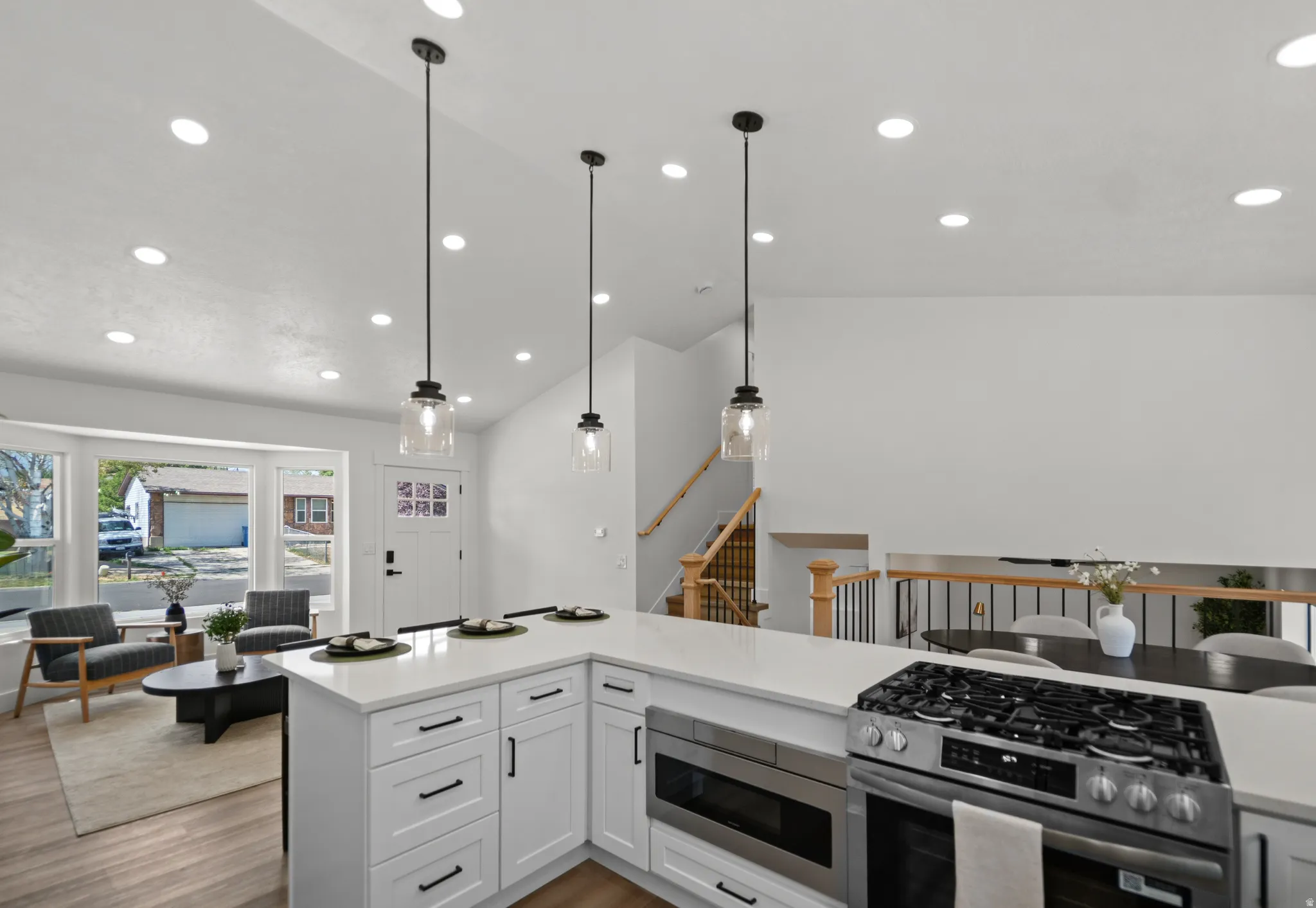 Open-concept kitchen with white cabinetry and a built-in stainless steel oven