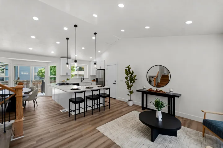 Open-concept living space featuring wood-finish flooring, recessed lighting, a vaulted ceiling, and a kitchen island with pendant lighting