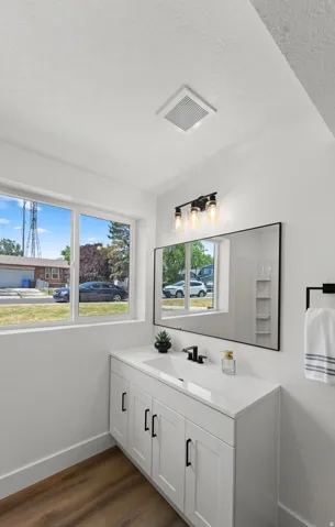 White vanity with black hardware, integrated rectangular sink, and matte black faucet